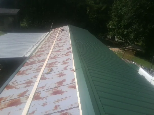 Old rusted panels beside newly installed green metal roofing — Wind Damage Roof Repair by Roofing Brothers in Kannapolis