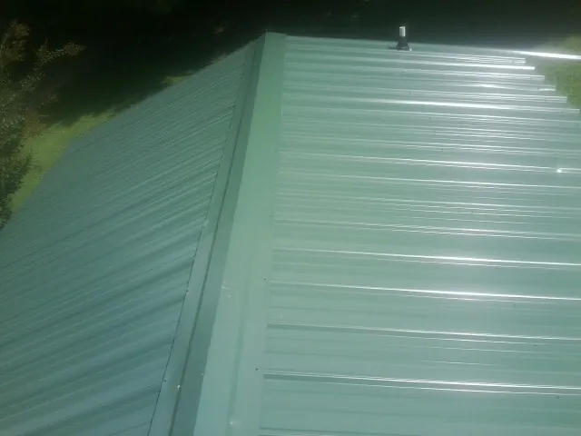 New green metal panels meeting at the ridge of a roof — Flat Roof Repair work by our crew in Kannapolis