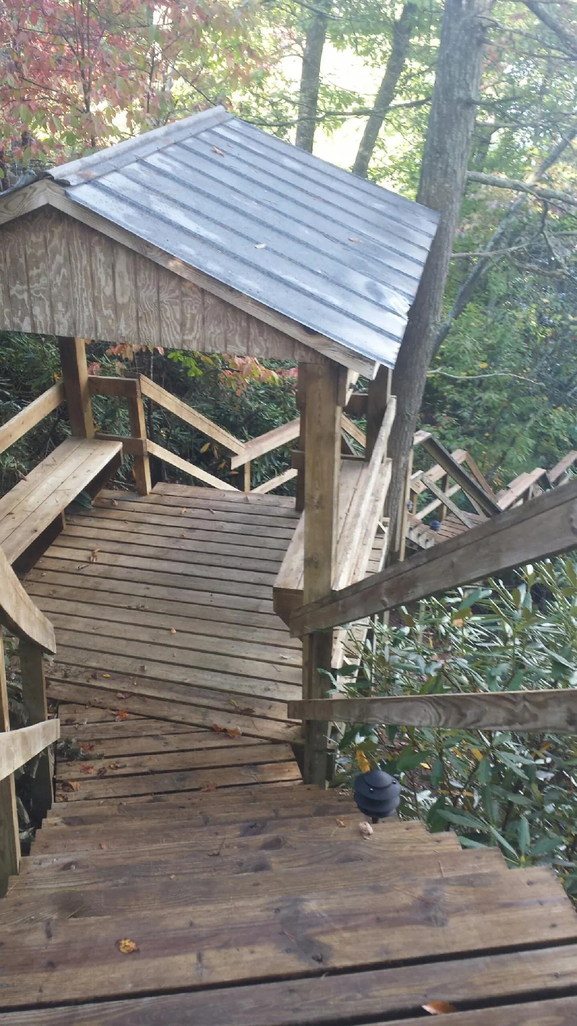Metal roofed shelter over wooden steps on a wooded walkway — Skylight Repair & Installation work by our crew in Kannapolis