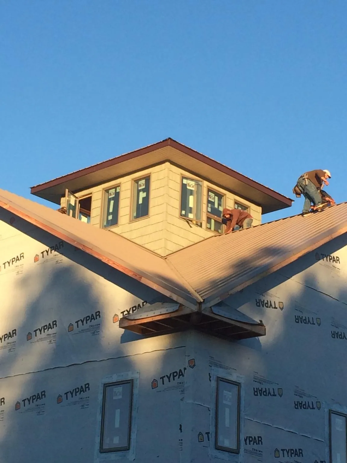 Roofers working around a rooftop cupola on a new metal roof at sunset — Roof Waterproofing in Kannapolis by Roofing Brothers